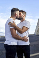 affectionate-gay-couple-kissing-on-bridge-against-sky-VEGF03088.jpg